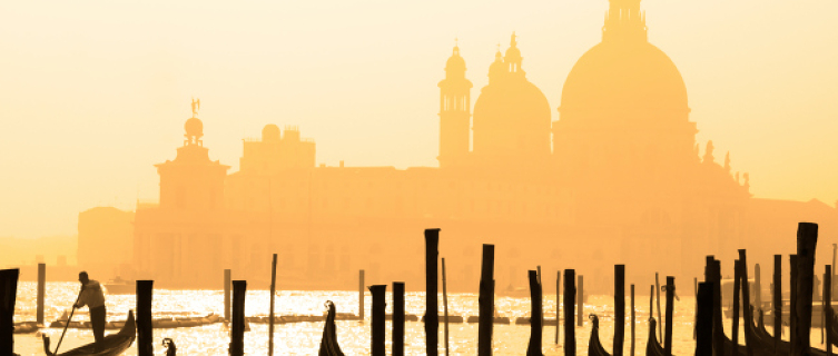 Gondolieri boats bob beneath a Venice sunset